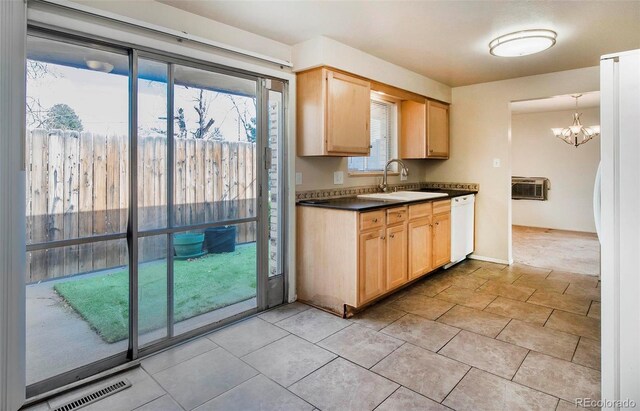 kitchen featuring dark countertops, a sink, light brown cabinets, and white appliances