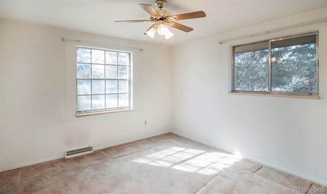 carpeted spare room with visible vents and a ceiling fan