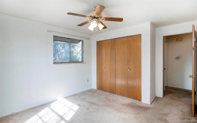 unfurnished bedroom featuring a closet, light colored carpet, and a ceiling fan