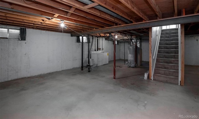 unfinished basement with stairway, independent washer and dryer, and water heater