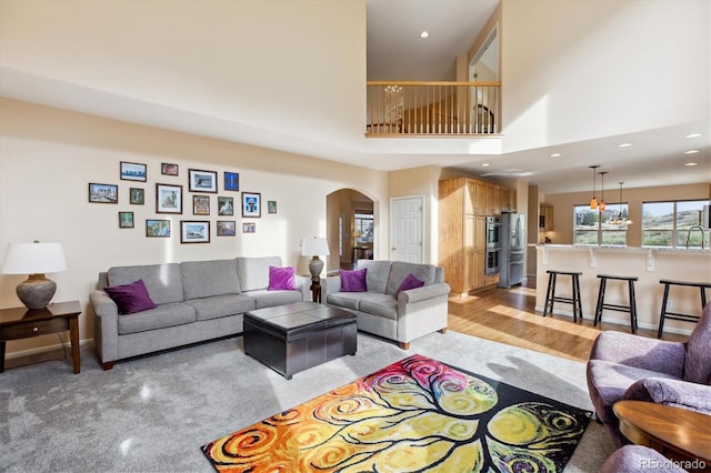 living room featuring a towering ceiling, arched walkways, baseboards, and recessed lighting