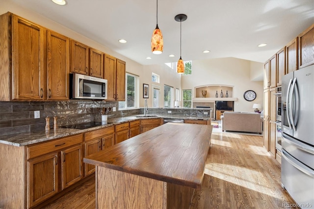 kitchen featuring a peninsula, brown cabinets, a sink, stainless steel appliances, and backsplash