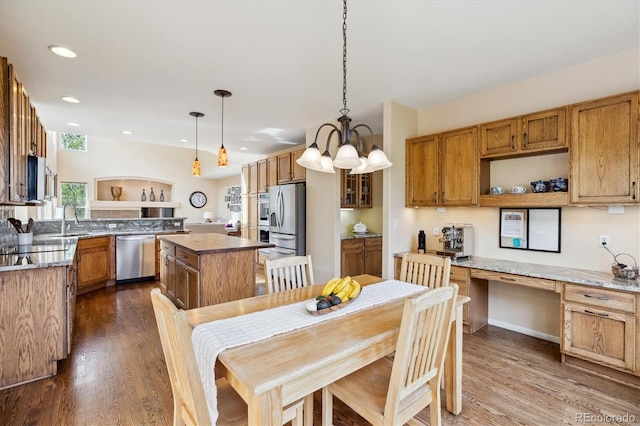 kitchen with dark wood-style flooring, a center island, appliances with stainless steel finishes, and a sink