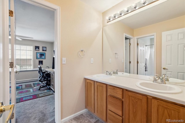 bathroom with double vanity, baseboards, and a sink