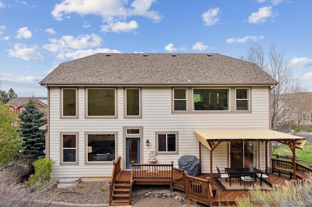 back of house featuring roof with shingles and a wooden deck