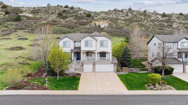 traditional-style house featuring an attached garage, stone siding, stairway, a front yard, and driveway