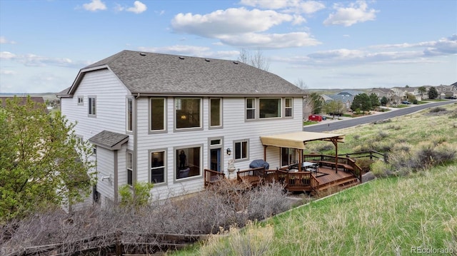 back of property with a deck and roof with shingles