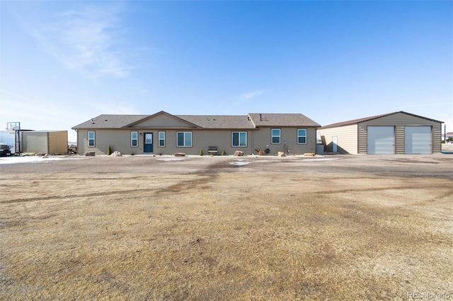 rear view of property with an outdoor structure and a detached garage