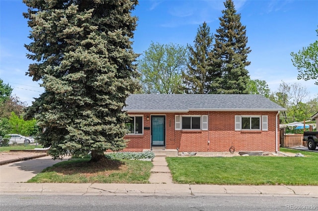 view of front of property with brick siding, a front yard, and roof with shingles