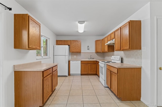 kitchen with white appliances, under cabinet range hood, a sink, light countertops, and backsplash