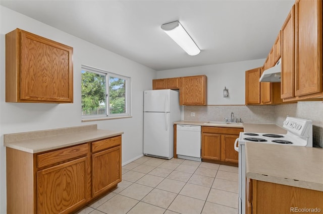 kitchen with white appliances, under cabinet range hood, a sink, decorative backsplash, and light countertops