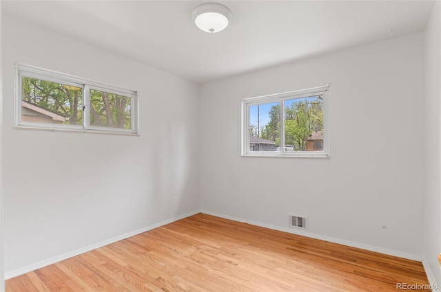 unfurnished room with healthy amount of natural light, baseboards, and light wood finished floors