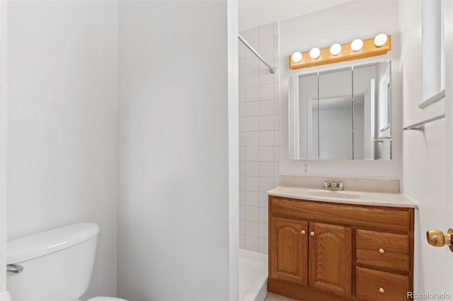 bathroom featuring tiled shower, toilet, and vanity