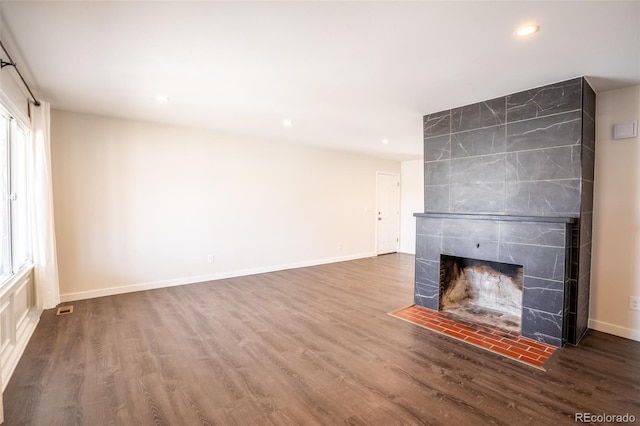 unfurnished living room featuring baseboards, recessed lighting, visible vents, a tile fireplace, and wood finished floors