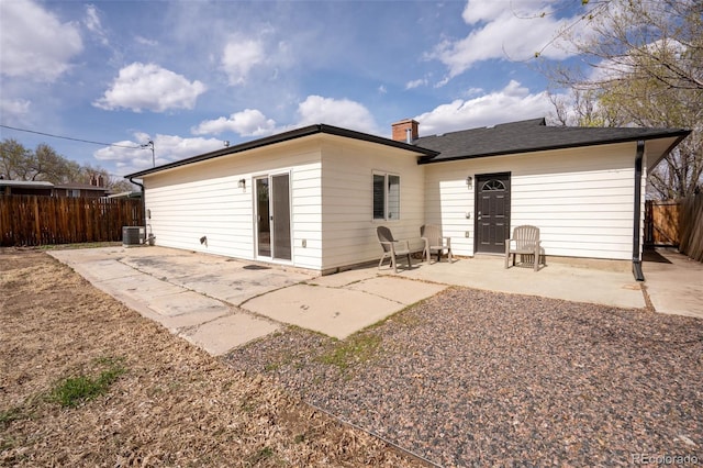 back of house featuring central air condition unit, a patio, a chimney, and fence