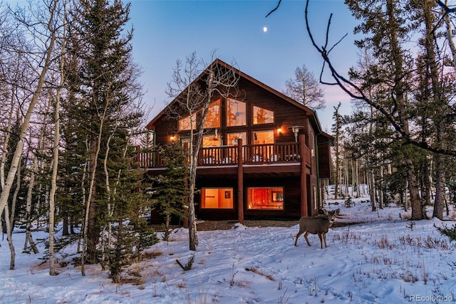 snow covered rear of property with a wooden deck