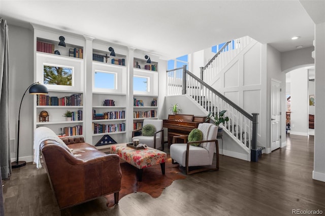 sitting room with arched walkways, wood finished floors, recessed lighting, baseboards, and stairway