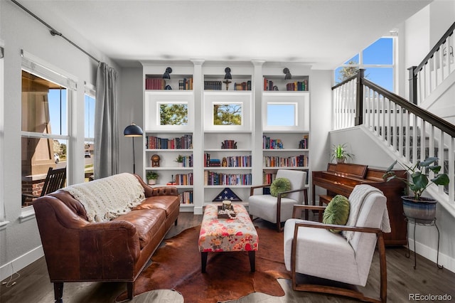 living area with baseboards, wood finished floors, and stairs