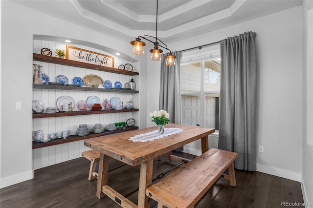 dining area with dark wood-style flooring, a raised ceiling, and baseboards