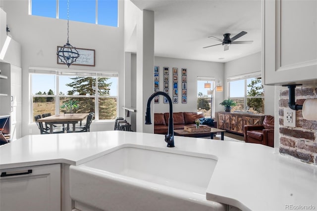 kitchen featuring a sink, light countertops, ceiling fan, decorative light fixtures, and open floor plan