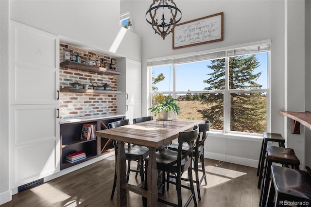 dining room with a chandelier, dark wood finished floors, baseboards, and a high ceiling