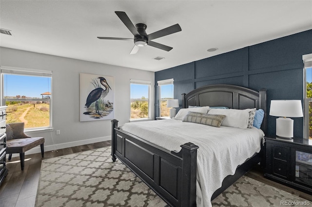bedroom featuring a decorative wall, wood finished floors, a ceiling fan, and baseboards