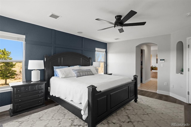 bedroom featuring arched walkways, wood finished floors, ceiling fan, and baseboards