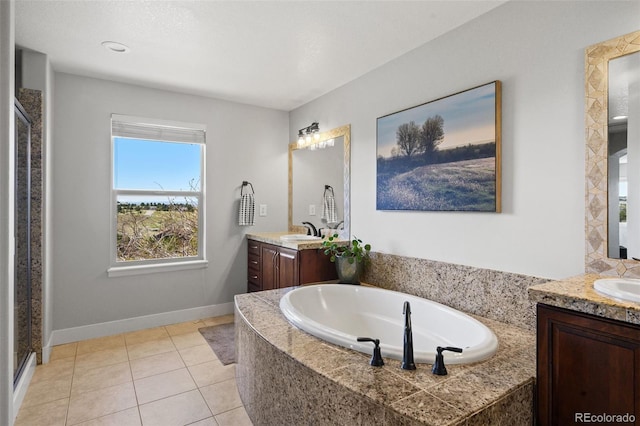 full bath featuring two vanities, a bath, baseboards, and tile patterned floors