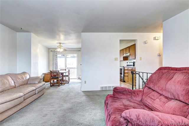 living area with visible vents, light carpet, and ceiling fan