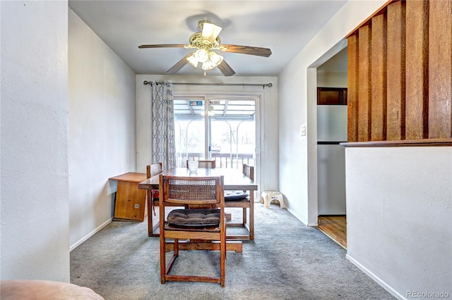 carpeted dining area featuring baseboards, ceiling fan, and a textured wall