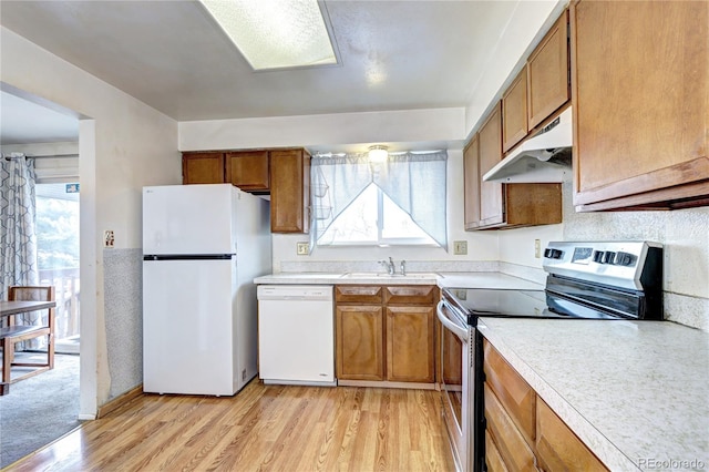 kitchen with under cabinet range hood, white appliances, brown cabinetry, and a sink