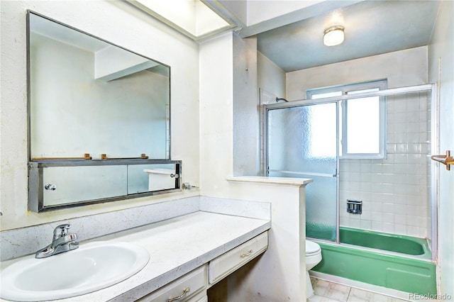 full bath with toilet, vanity, and shower / bath combination with glass door