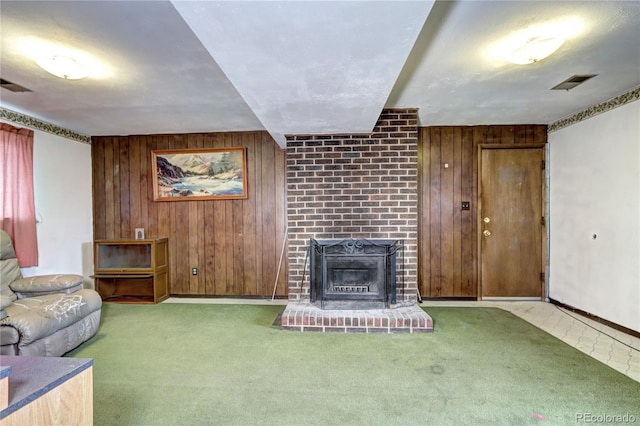 living room featuring a brick fireplace, wooden walls, carpet, and visible vents