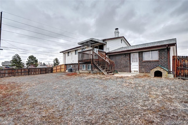 back of house featuring brick siding, cooling unit, stairs, and fence