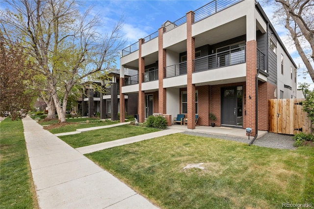 exterior space featuring brick siding, fence, and a front yard