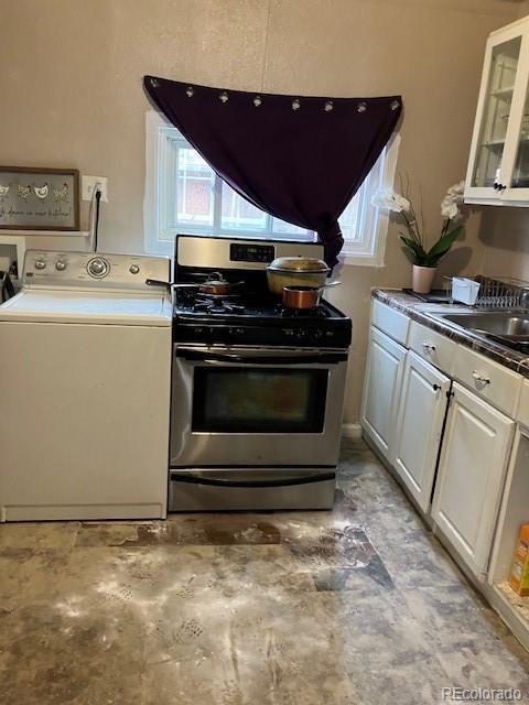 615 E 49th Ave, Denver, CO 80216 - kitchen featuring washer / dryer, stainless steel range with gas stovetop, a sink, glass insert cabinets, and dark countertops