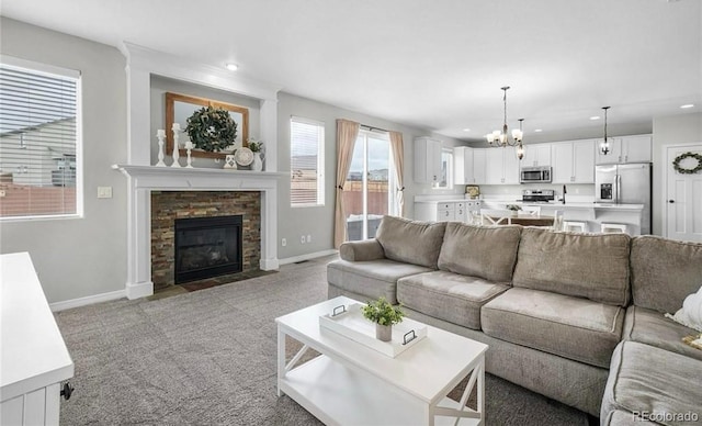 living room featuring carpet, an inviting chandelier, and a stone fireplace