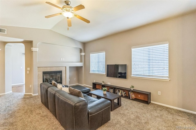 living area featuring a fireplace, carpet floors, arched walkways, vaulted ceiling, and visible vents