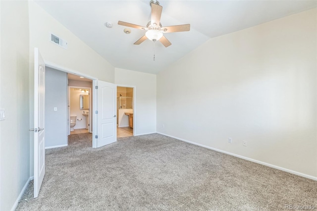 unfurnished bedroom featuring light carpet, ensuite bath, baseboards, lofted ceiling, and visible vents