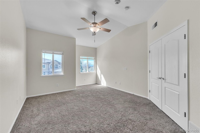 interior space featuring carpet, a ceiling fan, baseboards, lofted ceiling, and visible vents