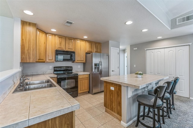 kitchen with visible vents, a sink, a kitchen island, and black appliances