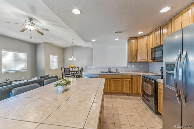 kitchen with visible vents, open floor plan, tile countertops, a sink, and black appliances