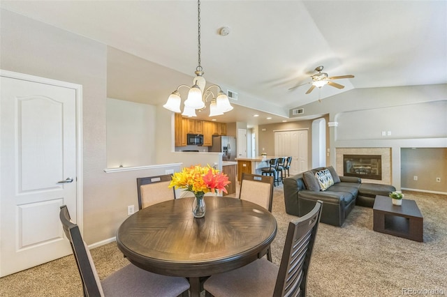 dining room featuring visible vents, light colored carpet, lofted ceiling, and ceiling fan with notable chandelier