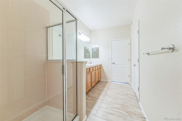 bathroom featuring vanity, baseboards, and a shower stall