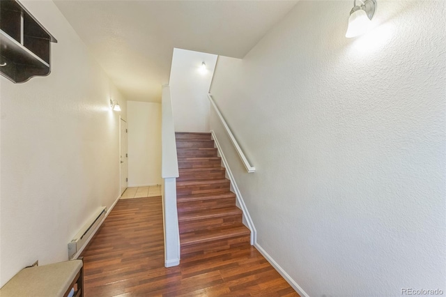 staircase with baseboards, a baseboard radiator, and wood finished floors