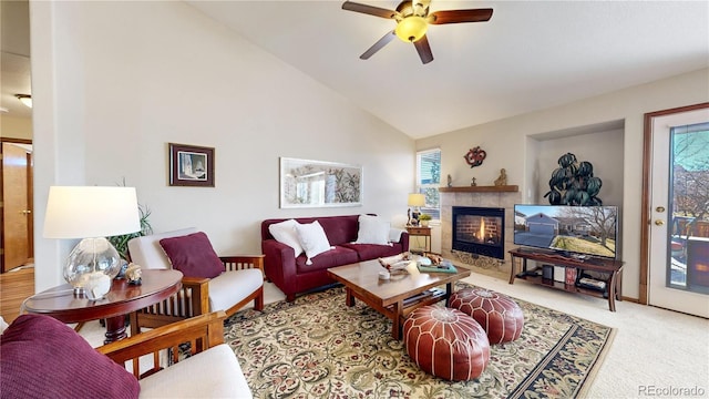 carpeted living room featuring a tiled fireplace, ceiling fan, and high vaulted ceiling