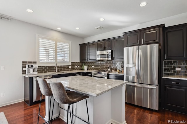 kitchen featuring sink, backsplash, stainless steel appliances, dark hardwood / wood-style floors, and a center island