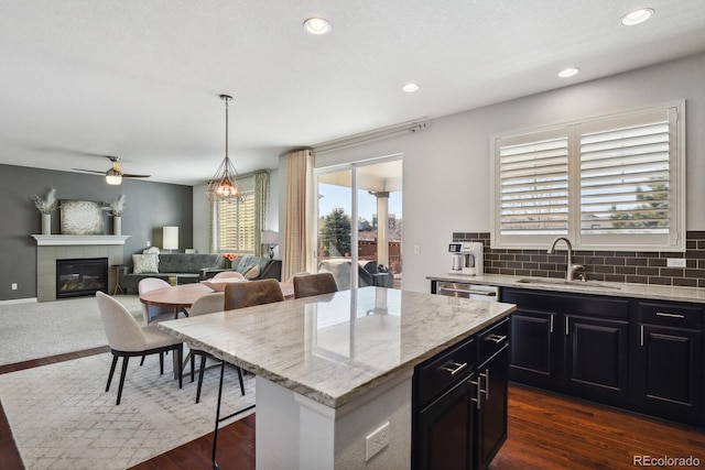 kitchen with a breakfast bar, sink, a kitchen island, pendant lighting, and a tiled fireplace