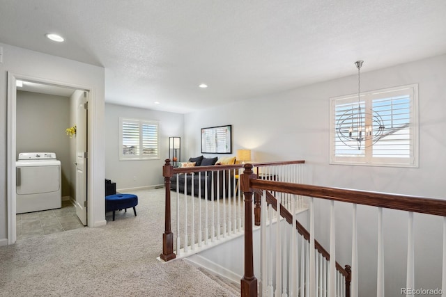 hall with washer / clothes dryer, light carpet, a textured ceiling, and an inviting chandelier