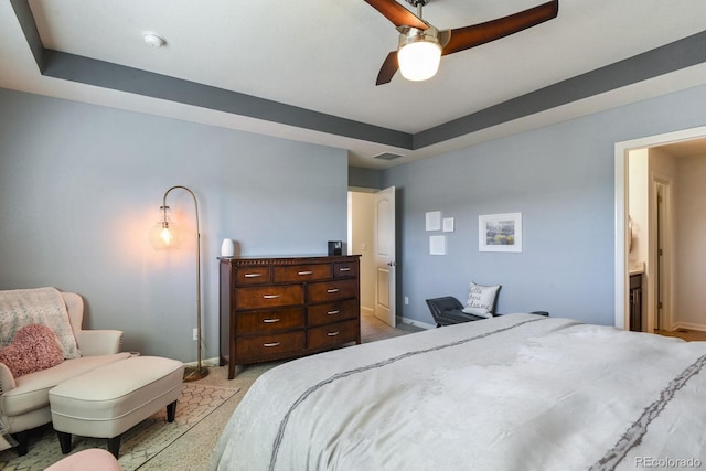 carpeted bedroom with a raised ceiling and ceiling fan